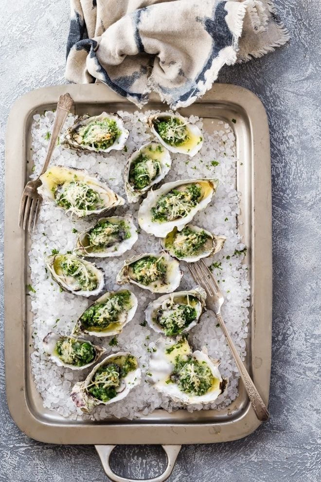 Oysters Rockefeller on a silver baking sheet.