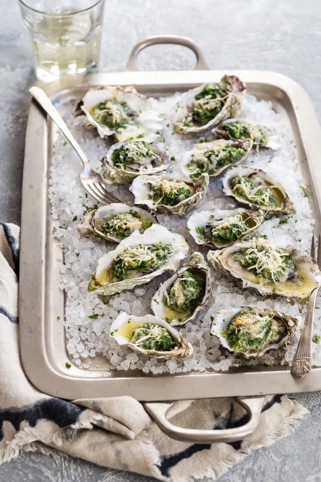 Oysters Rockefeller on a silver baking sheet.