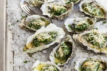 Oysters Rockefeller on a sheet pan with ice.