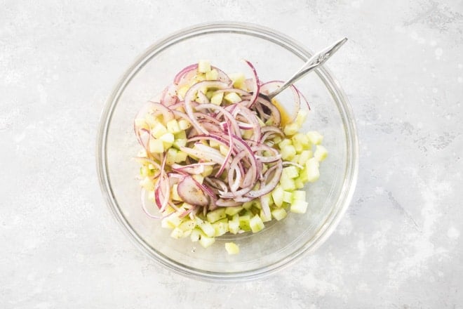 Mediterranean chopped salad ingredients in a clear bowl.