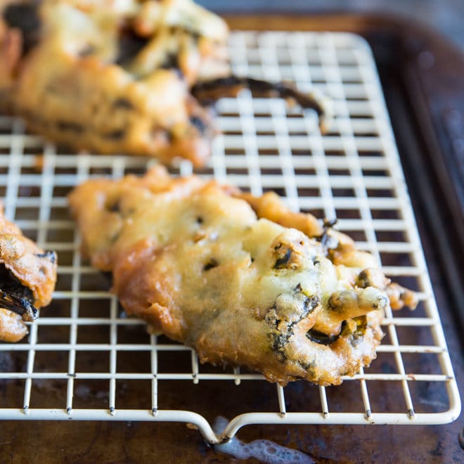 Freshly fried chile rellenos on a cooling rack.