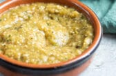 Chipotle tomatillo green chili salsa in a red bowl and a bowl of chips.