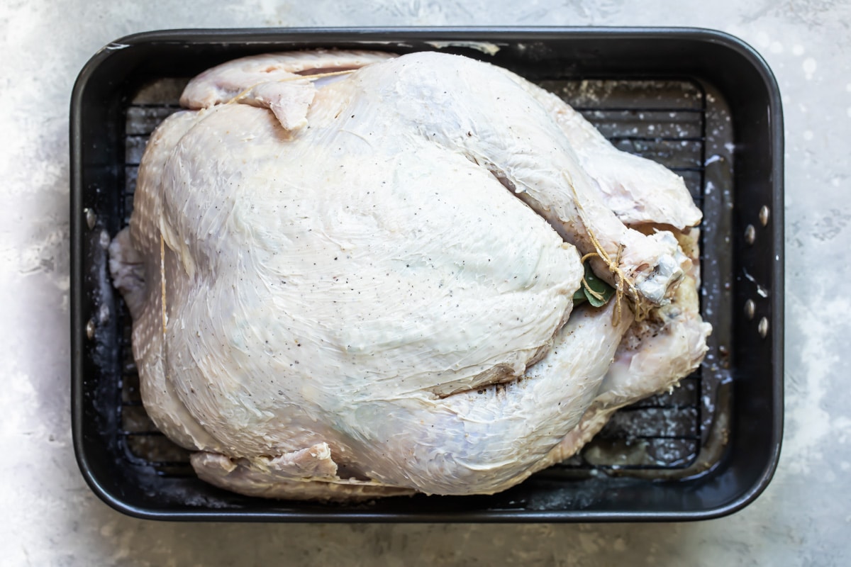 A raw trussed turkey in a roasting pan.