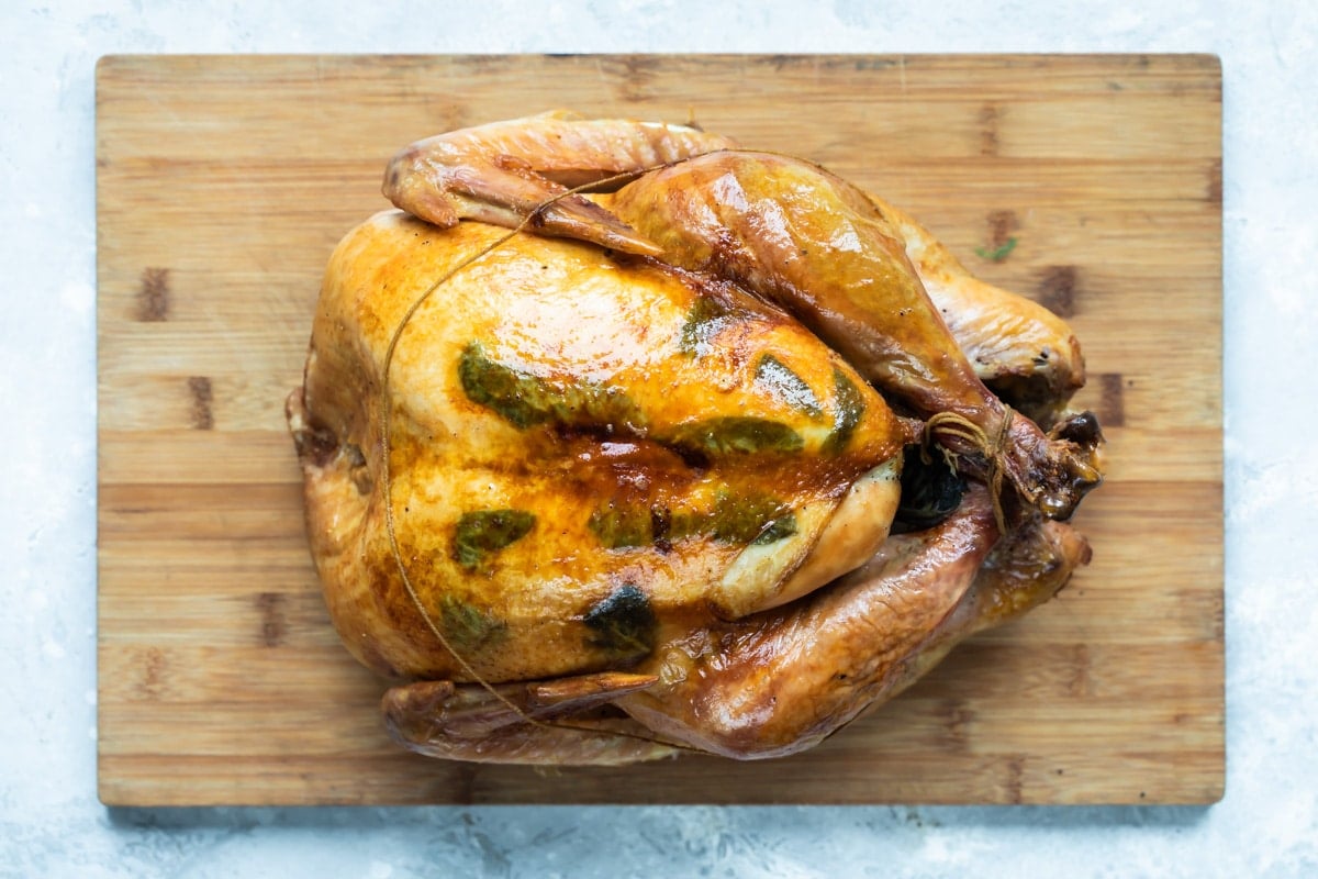 A trussed, roasted turkey resting on a cutting board.