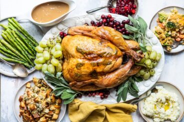 A roasted turkey on a platter with fruit.