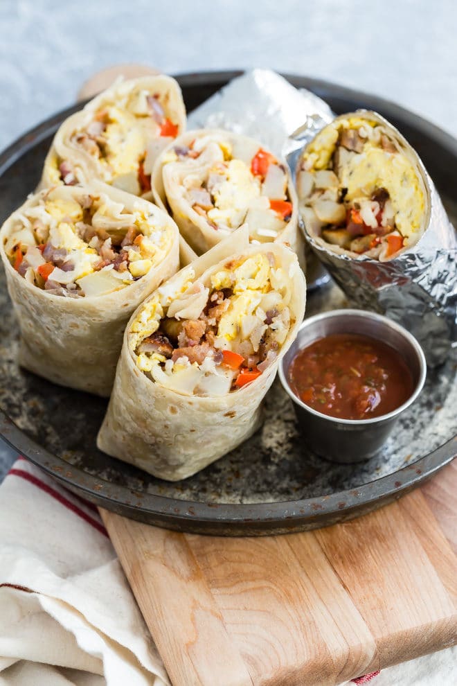 A black plate filled with breakfast burrito halves.