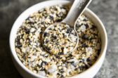 Everything bagel seasoning in a white bowl with a teaspoon.