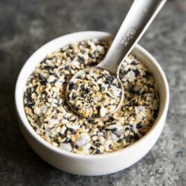 Everything bagel seasoning in a white bowl with a teaspoon.