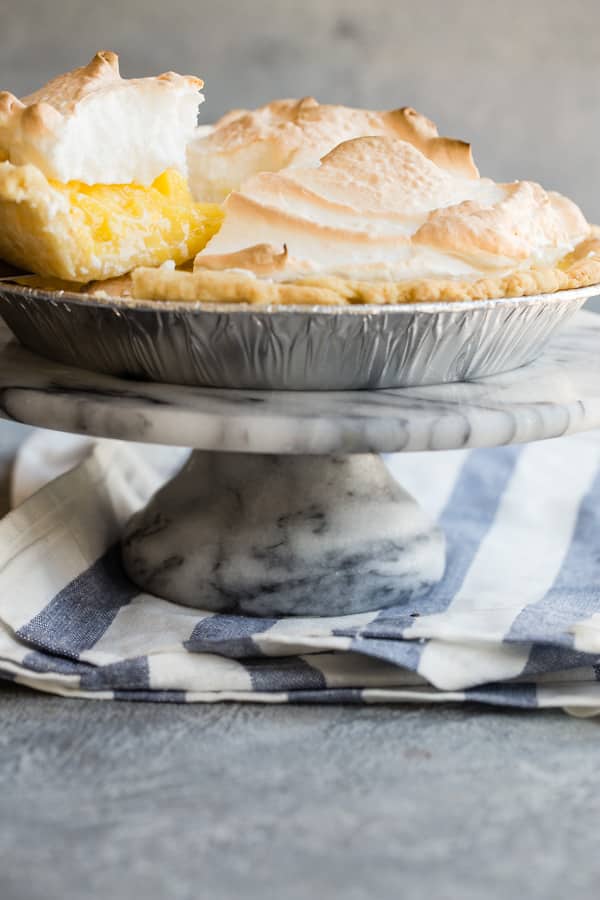 A side shot of a lemon meringue pie with a piece being lifted out.