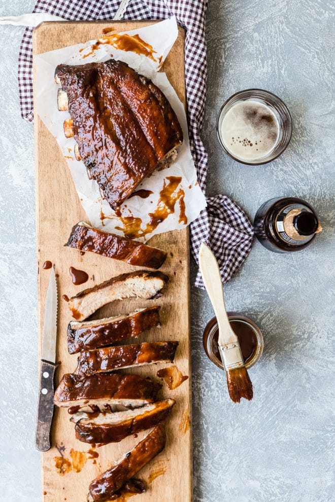 A rack of barbecue ribs on a wooden cutting board.