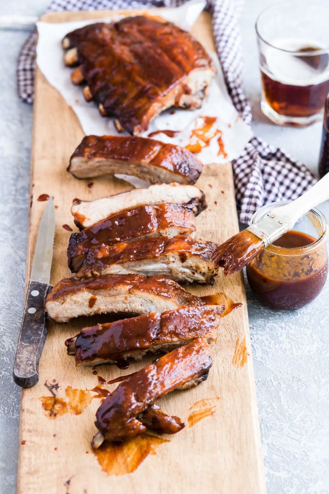 A rack of barbecue ribs on a wooden cutting board.