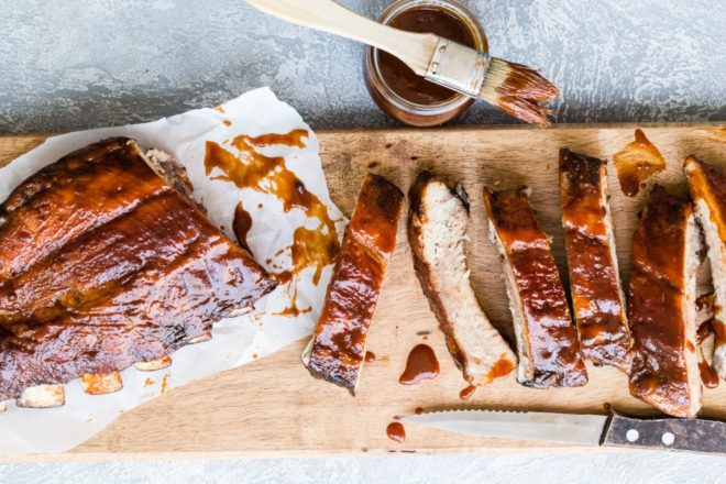 A rack of barbecue ribs on a wooden cutting board.