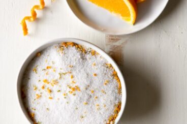 Margarita salt on a white plate with slices of an orange on another white plate.