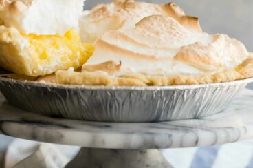 A lemon meringue pie with a piece being lifted out.