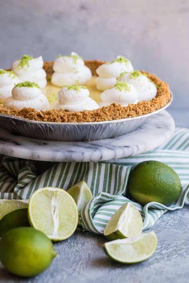 A key lime pie on a marble cake stand.