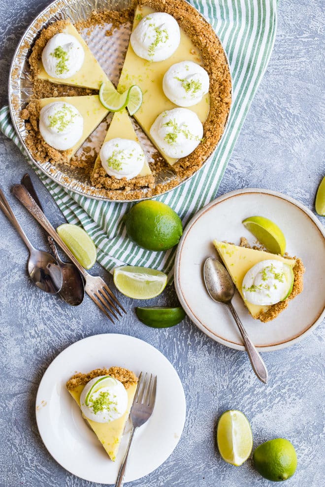 A key lime pie with two slices removed and plated next to the pie tin.