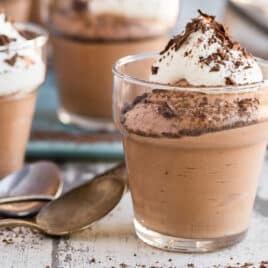 Small cups of chocolate mousse next to spoons.