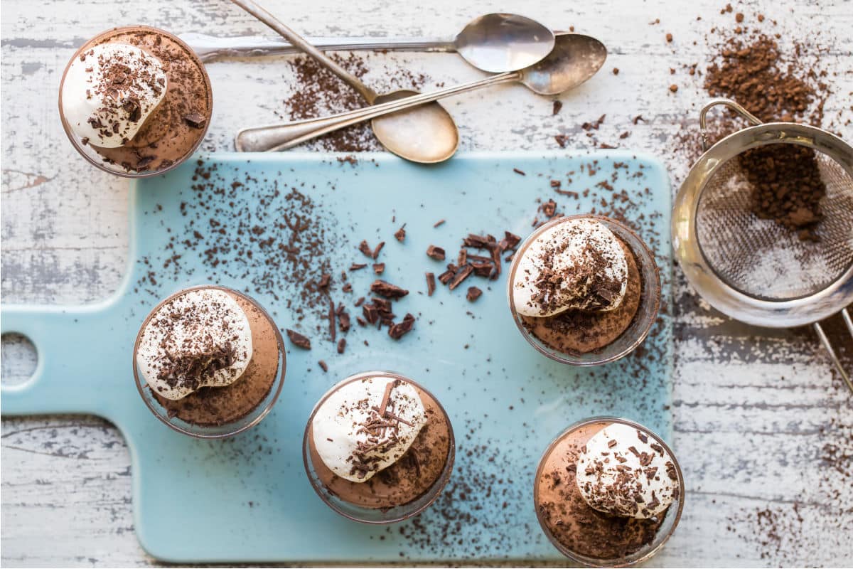 Small cups of chocolate mousse next to spoons.