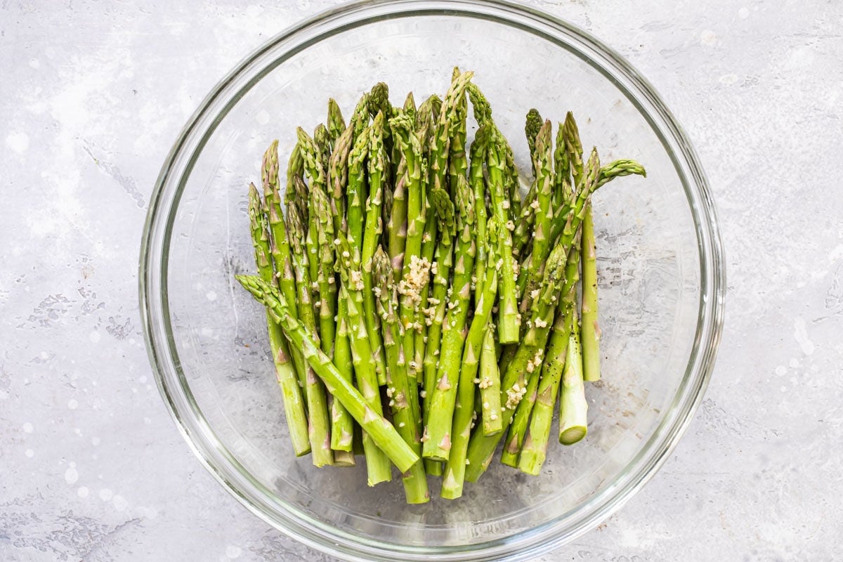 Raw asparagus in a bowl with garlic.