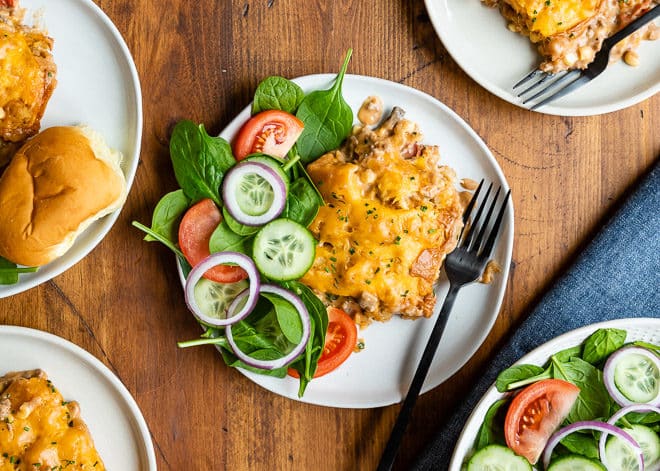Cowboy casserole on a white plate with a fork and salad.