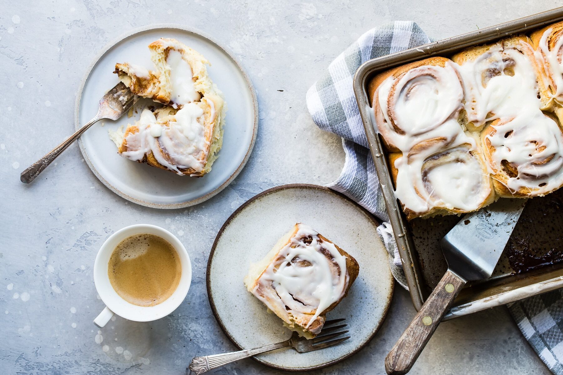 Cinnamon rolls on a plate next to pan of them.