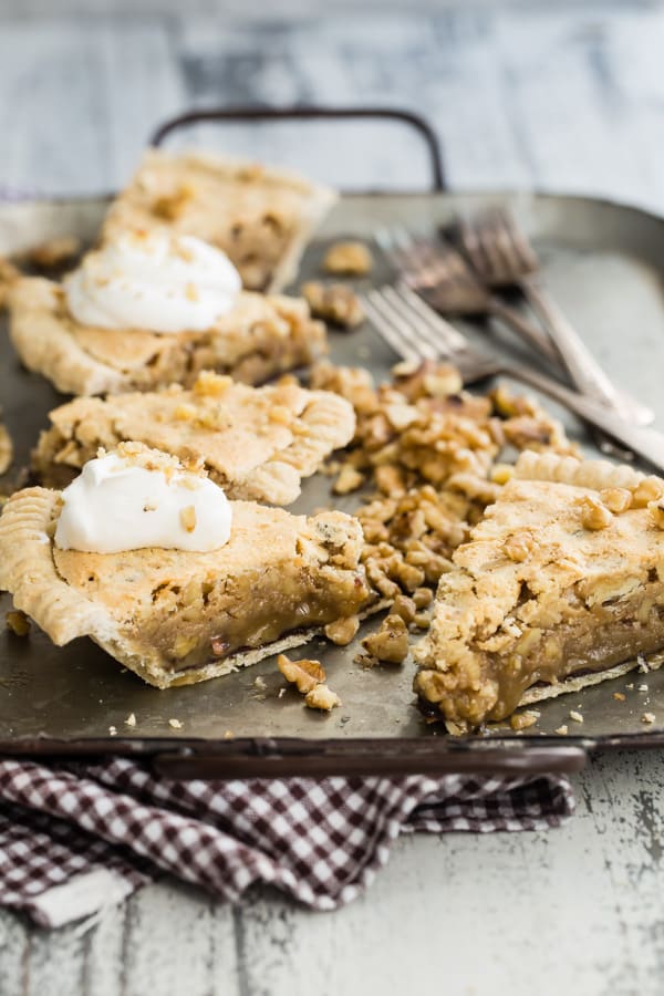 Chocolate walnut pie cut into slices on a black platter.
