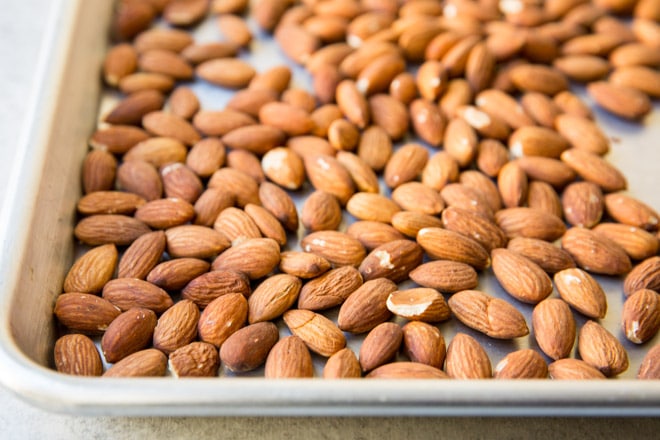 An overhead shot of whole almonds on a roasting pan.