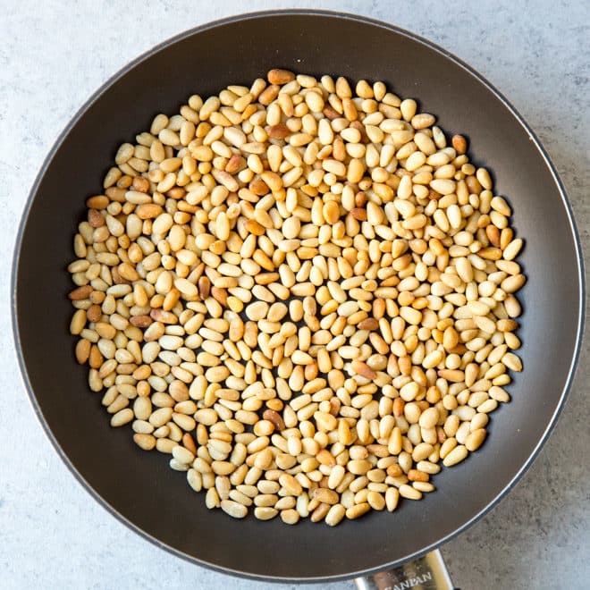 An overhead shot of pine nuts in a skillet.