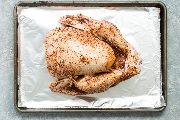 Overhead shot of raw turkey with rub on a sheet pan