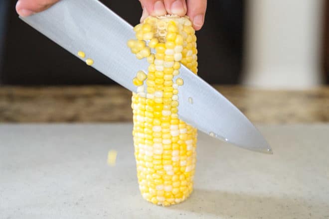 Corn being cut off of a cob.