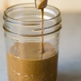 Tahini being poured into a mason jar.