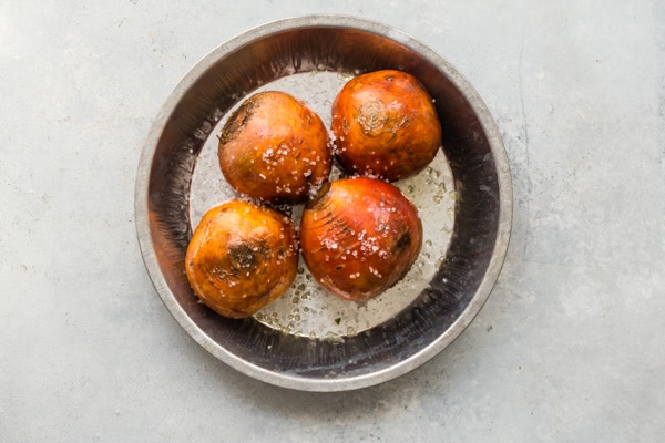 An overhead shot of roasted beets in a round baking pan.
