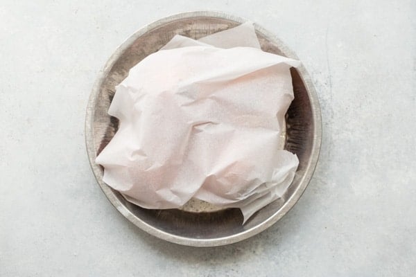 An overhead shot of beets wrapped up in paper in a round baking pan.