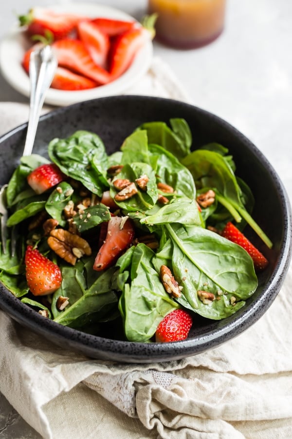 Strawberry spinach salad in a black bowl.