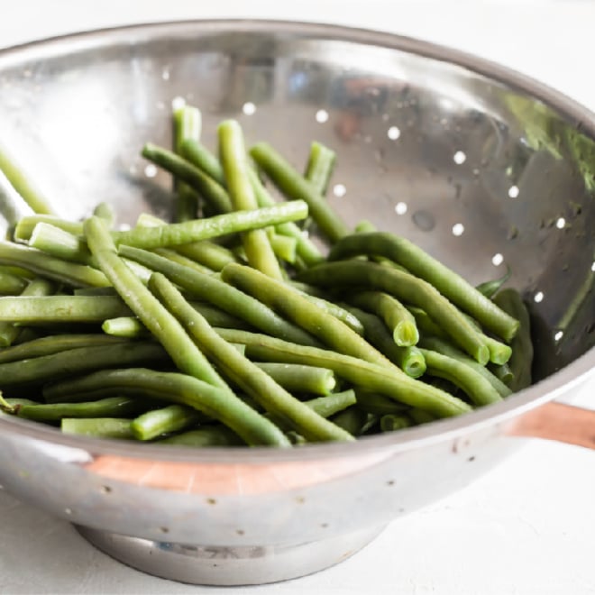 Green beans in a sliver colander.