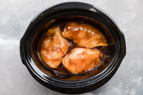 An overhead shot of slow cooker pulled chicken ingredients in a crockpot before being cooked.
