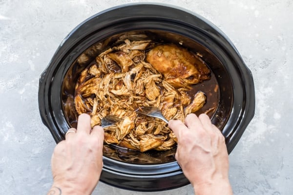An overhead shot of slow cooker pulled chicken in a crockpot after being cooked.