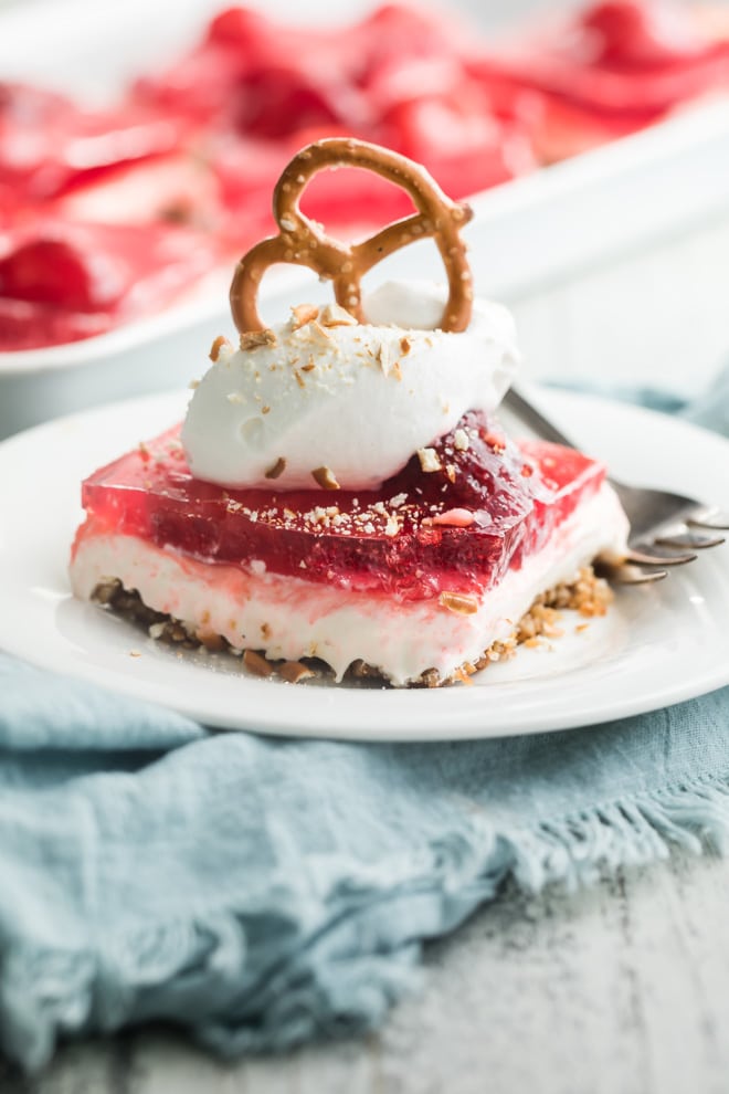 A serving of strawberry pretzel salad on a white plate with a fork.