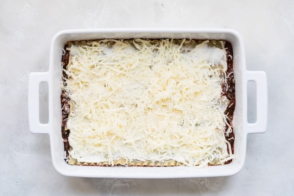 Vegetable lasagna precooked in a white baking dish.