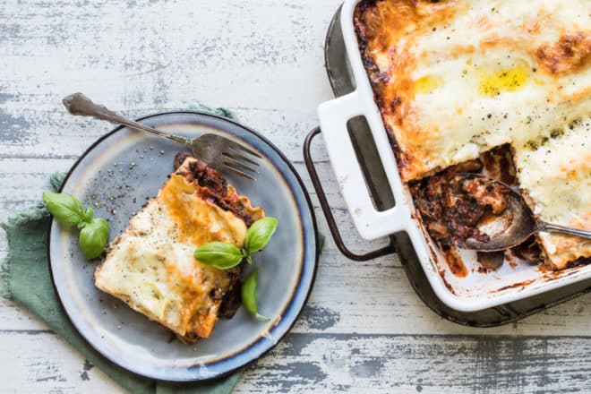 Vegetable lasagna on a blue plate and in a white baking dish.