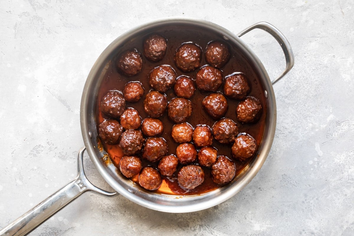 Meatballs, chili sauce, and grape jelly in a skillet.