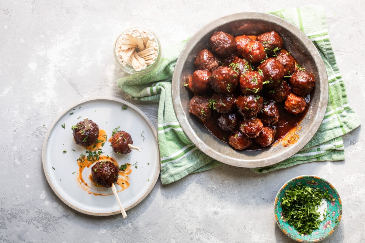 Crockpot meatballs with grape jelly sauce in a silver bowl.