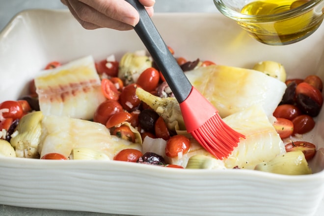 Baked cod in a white baking dish.