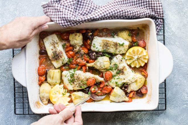 Baked cod in a white baking dish.