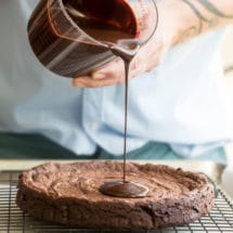 Chocolate glaze being poured onto a flourless chocolate cake.