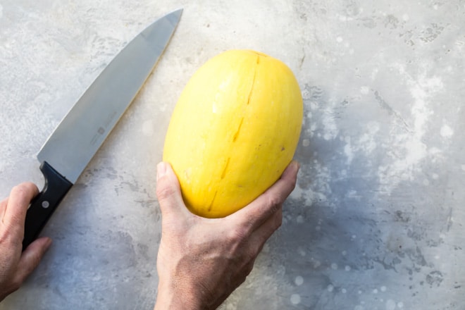 A whole yellow squash and a silver knife.