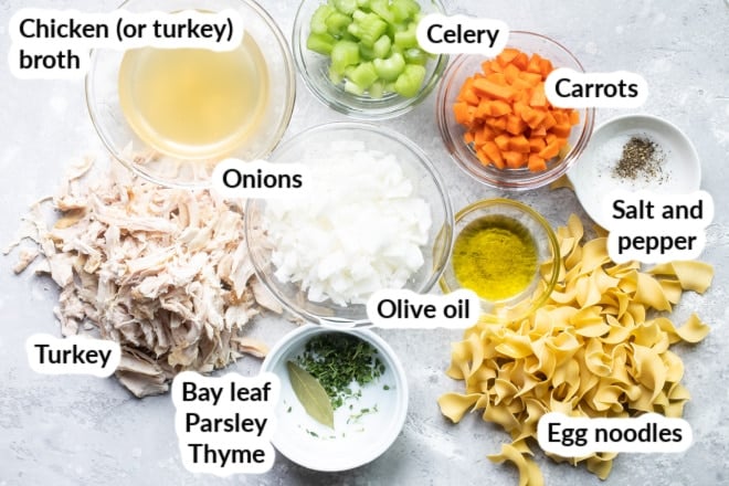 Labeled turkey noodle soup ingredients in bowls.