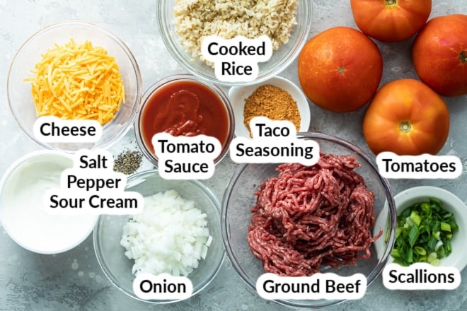 Taco stuffed tomato ingredients labeled and in various bowls.