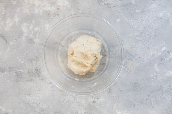 Danish kringle dough rolled into a ball in a clear bowl.