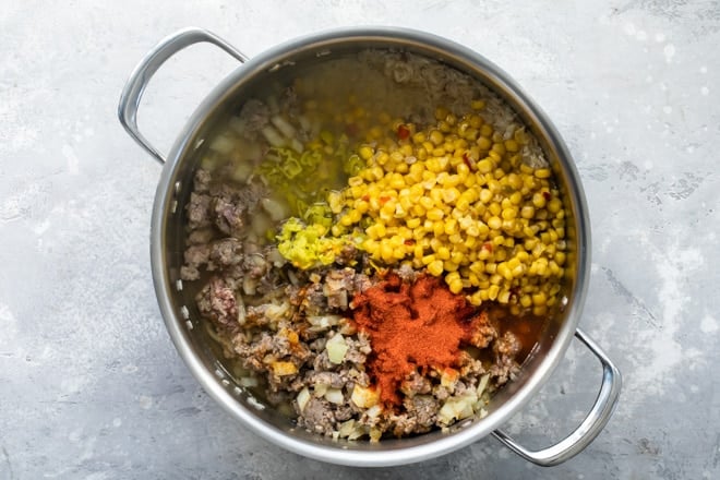 One pot Puerto Rican rice ingredients being added together in a silver pot.